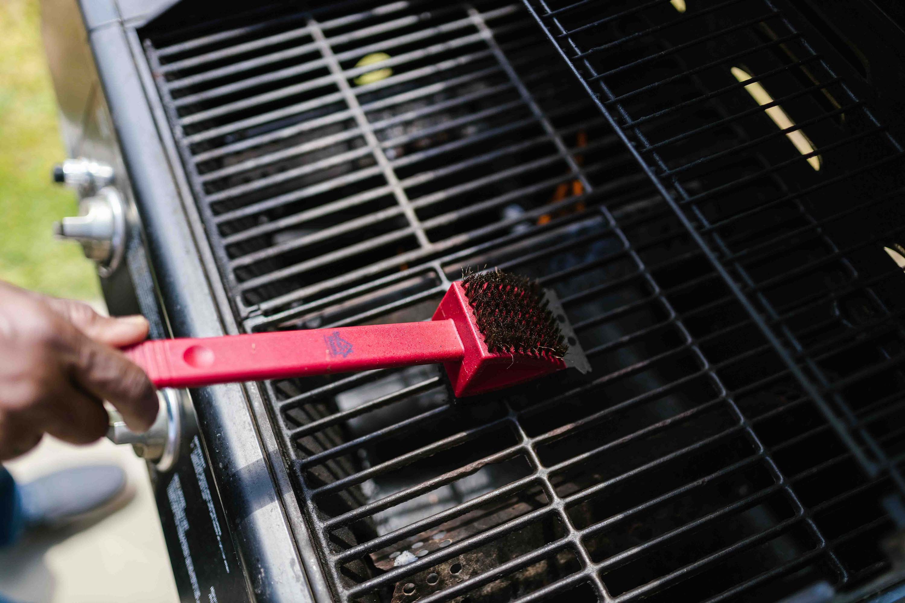 A person cleaning a barbecue